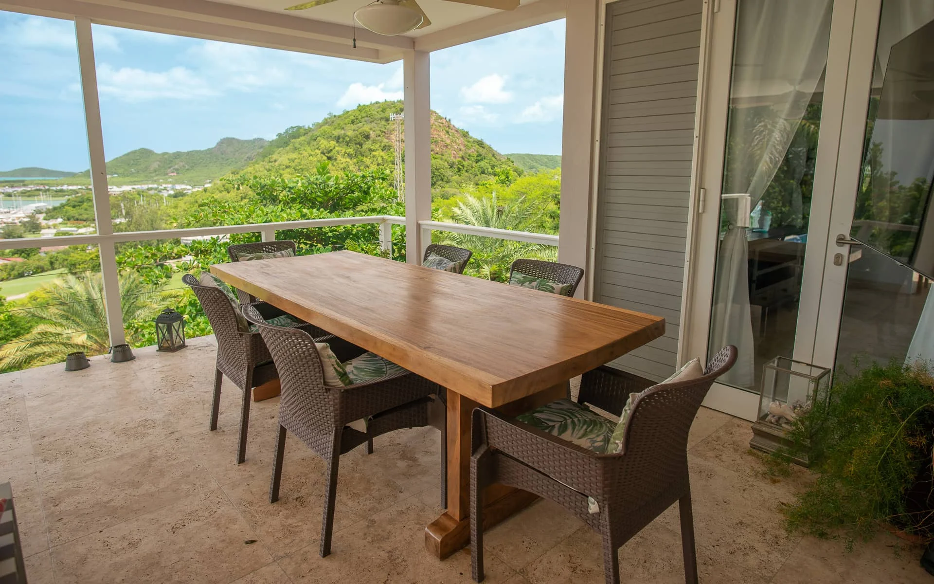 Covered dining terrace with a teak table looking out over green Antigua hills