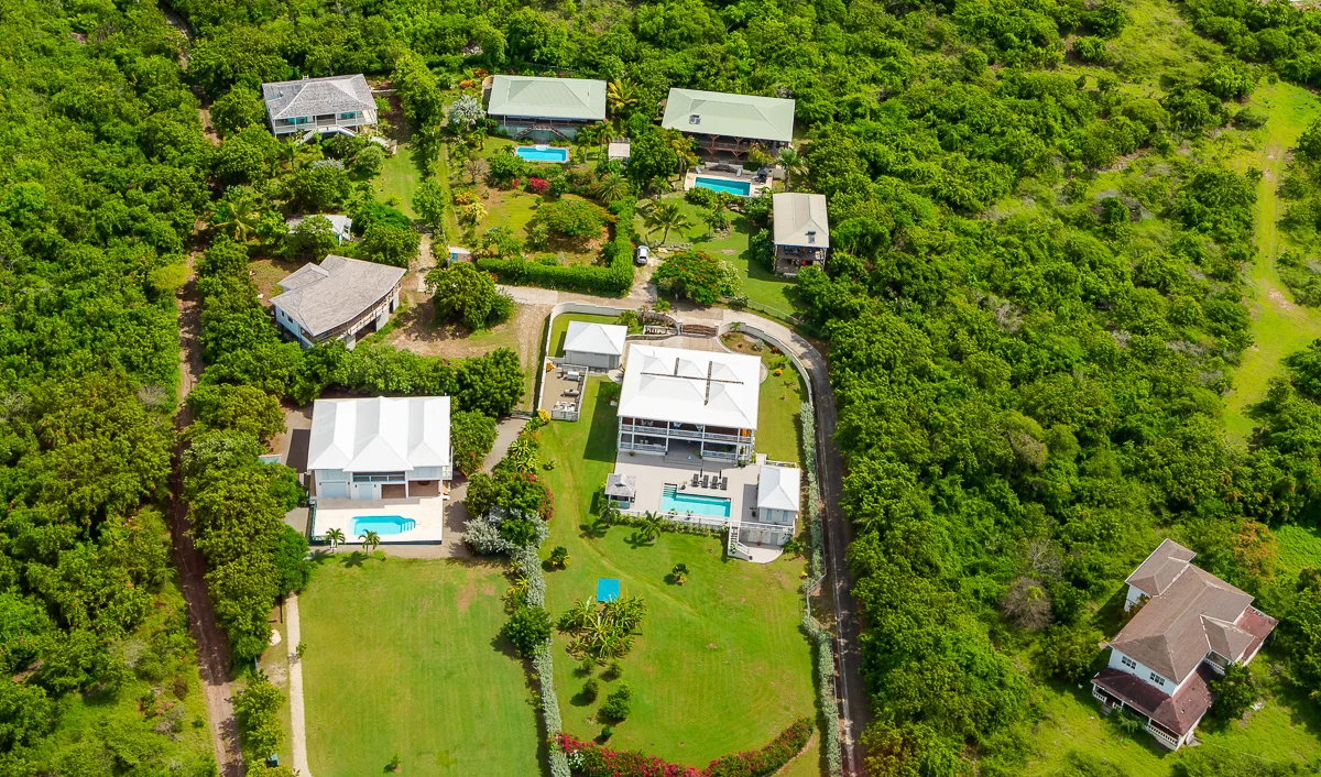 Aerial view of hillside villas with private pools on the Antigua coastline