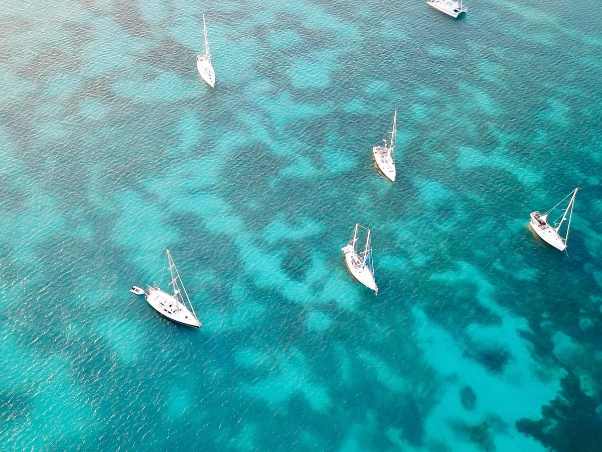 Yachts at anchor over a turquoise reef, seen from directly above