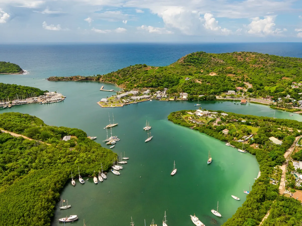 Aerial view of a sheltered Antigua harbour, yachts at anchor between green hillsides