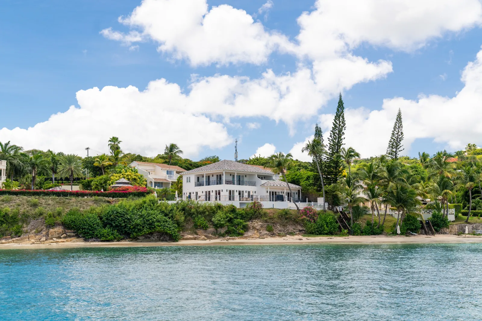 A white beachfront villa above the shoreline in Antigua, seen from the water