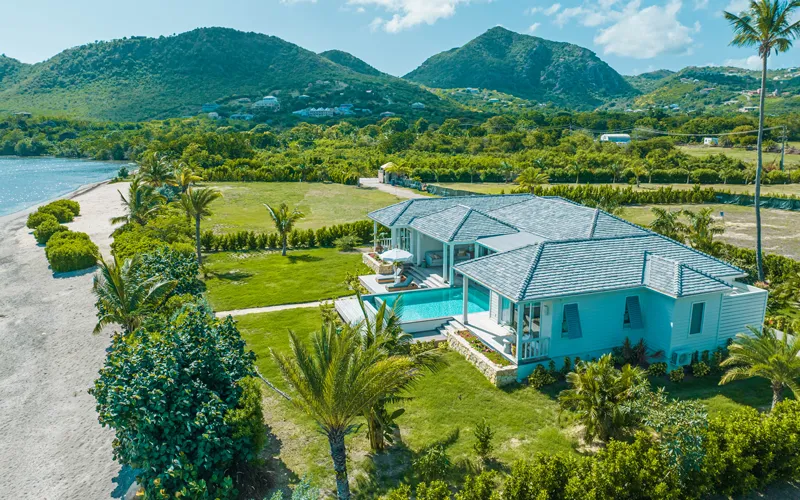 Aerial view of a beachfront villa and pool at The Beach Houses, with the coastline and hills beyond, Antigua